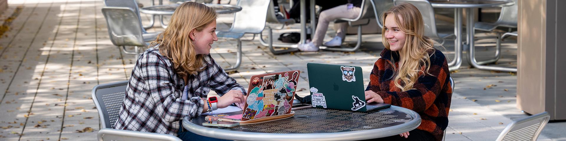 两个女学生坐在盖奇外面的笔记本电脑上